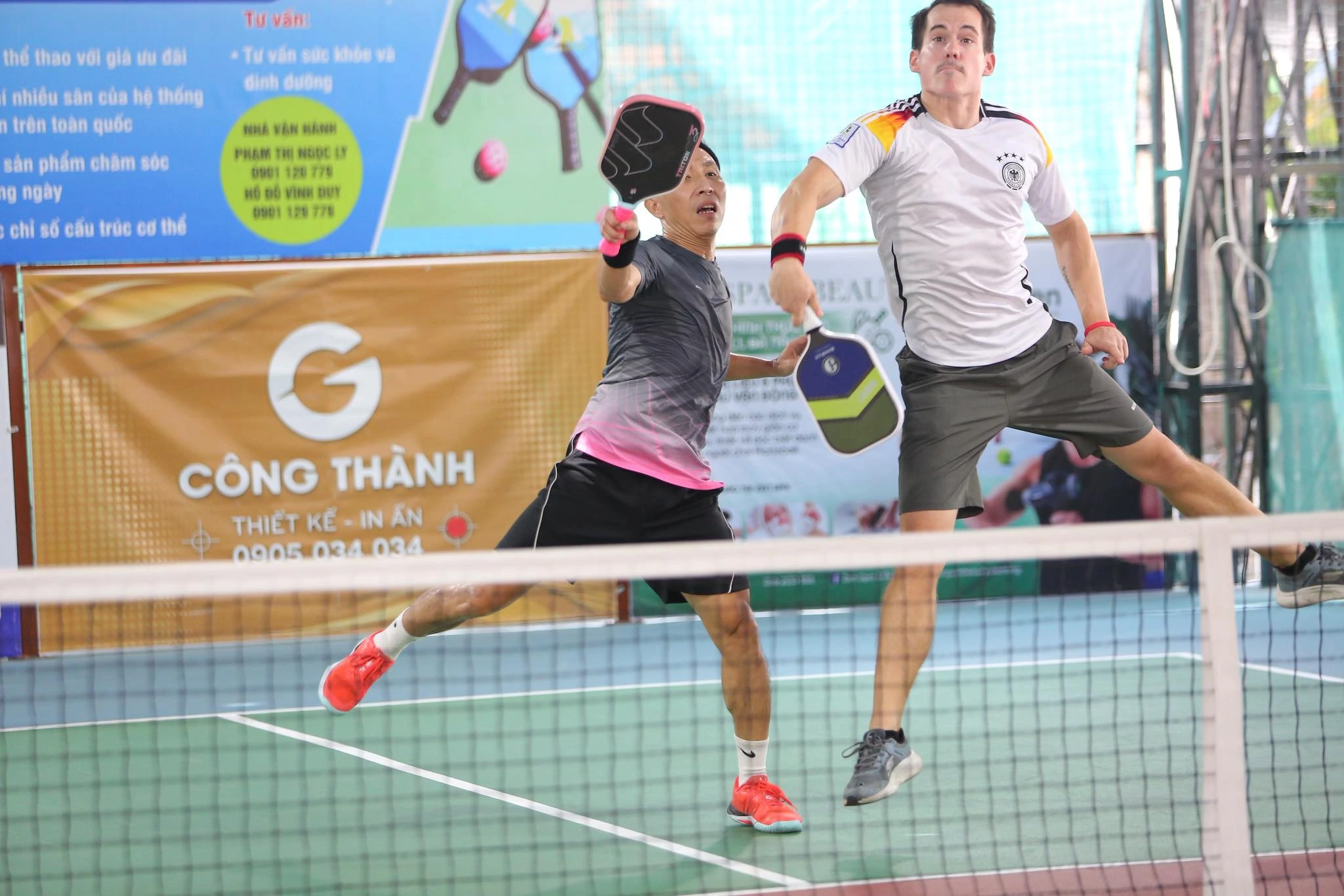 Two players in a team competing in a pickleball doubles match at Courtyard Pickle, Da Nang